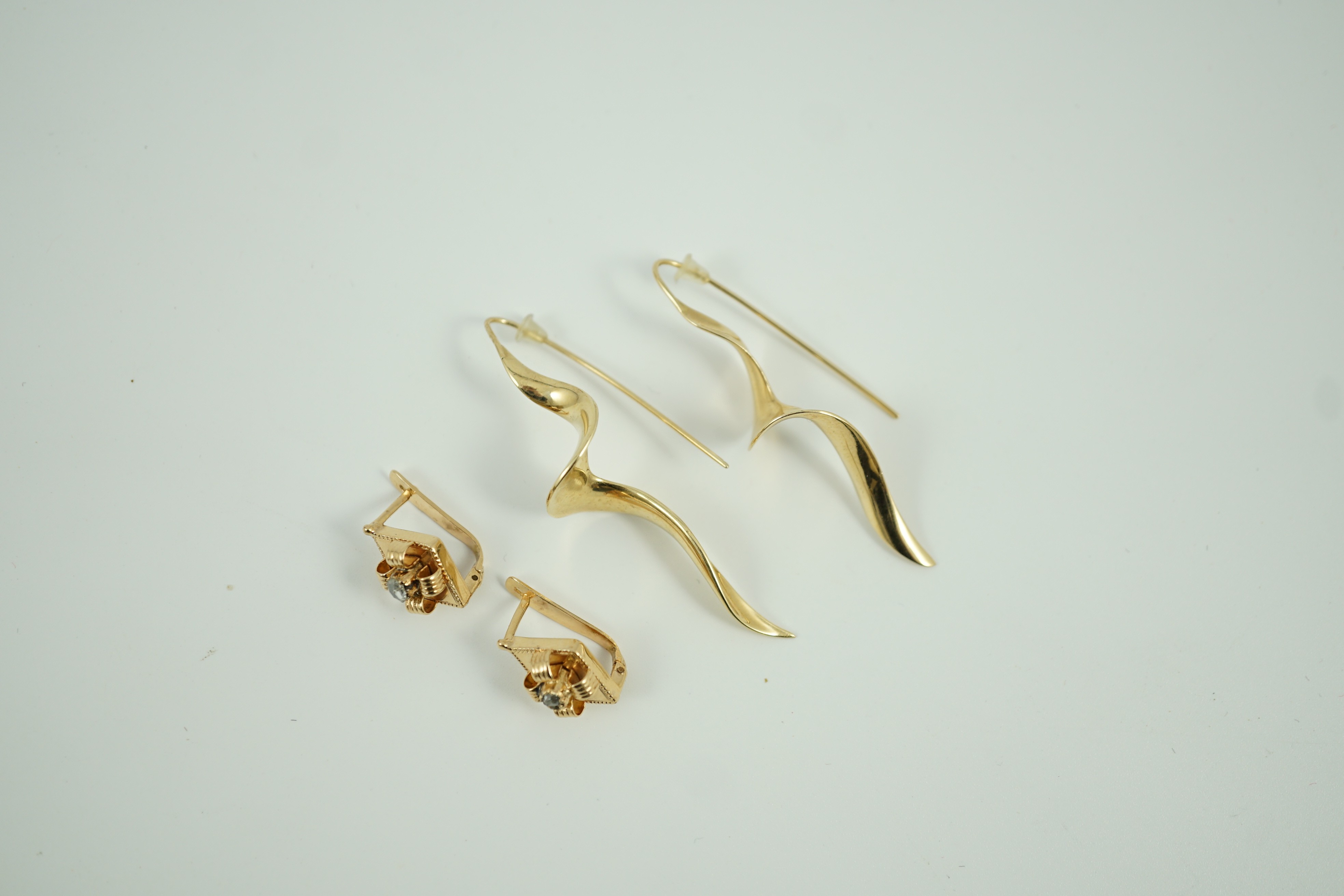A modern pair of 14k spiral earrings, 50mm, 6.4 grams and a part of yellow metal and solitaire rose cut diamond set earrings, gross 4.2 grams.